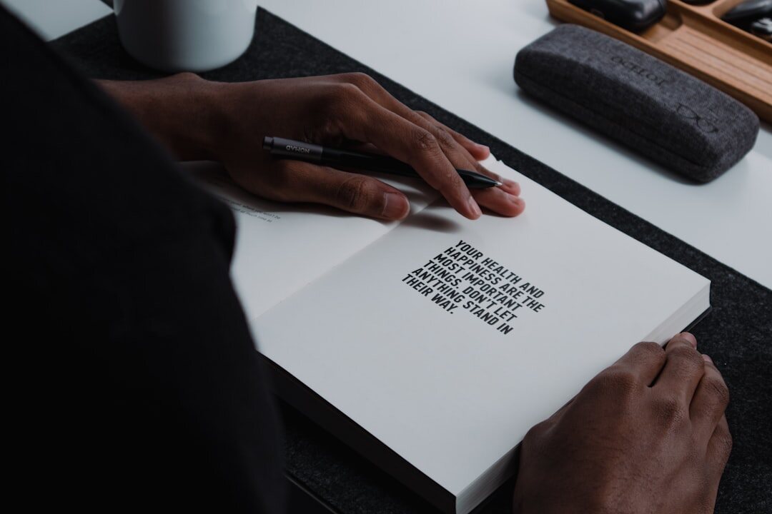 Hands writing a speech outline in a notebook next to a laptop