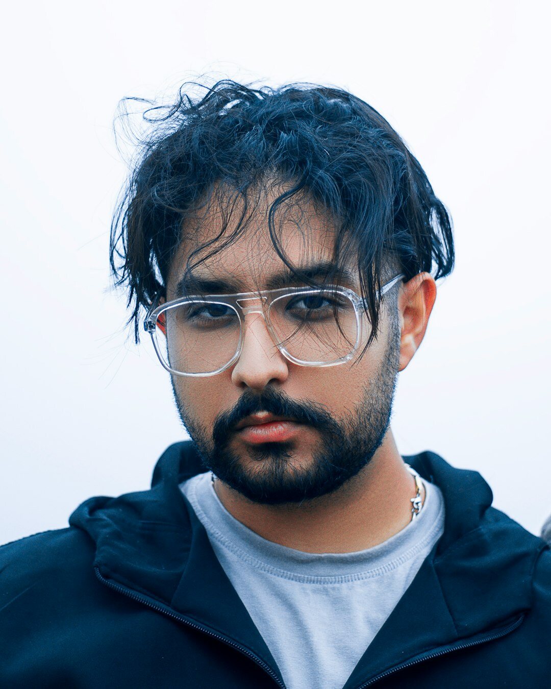 Studio headshot of a man with beard and glasses